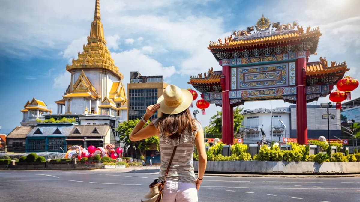 Solo female traveler exploring Bangkok Chinatown with golden temple and ornate gate