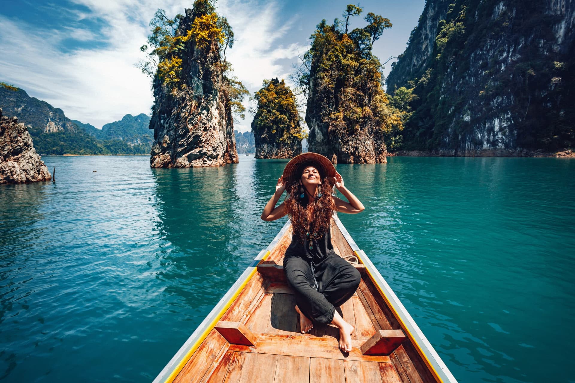 Happy traveler on longtail boat enjoying Thailand's stunning limestone karsts and turquoise waters