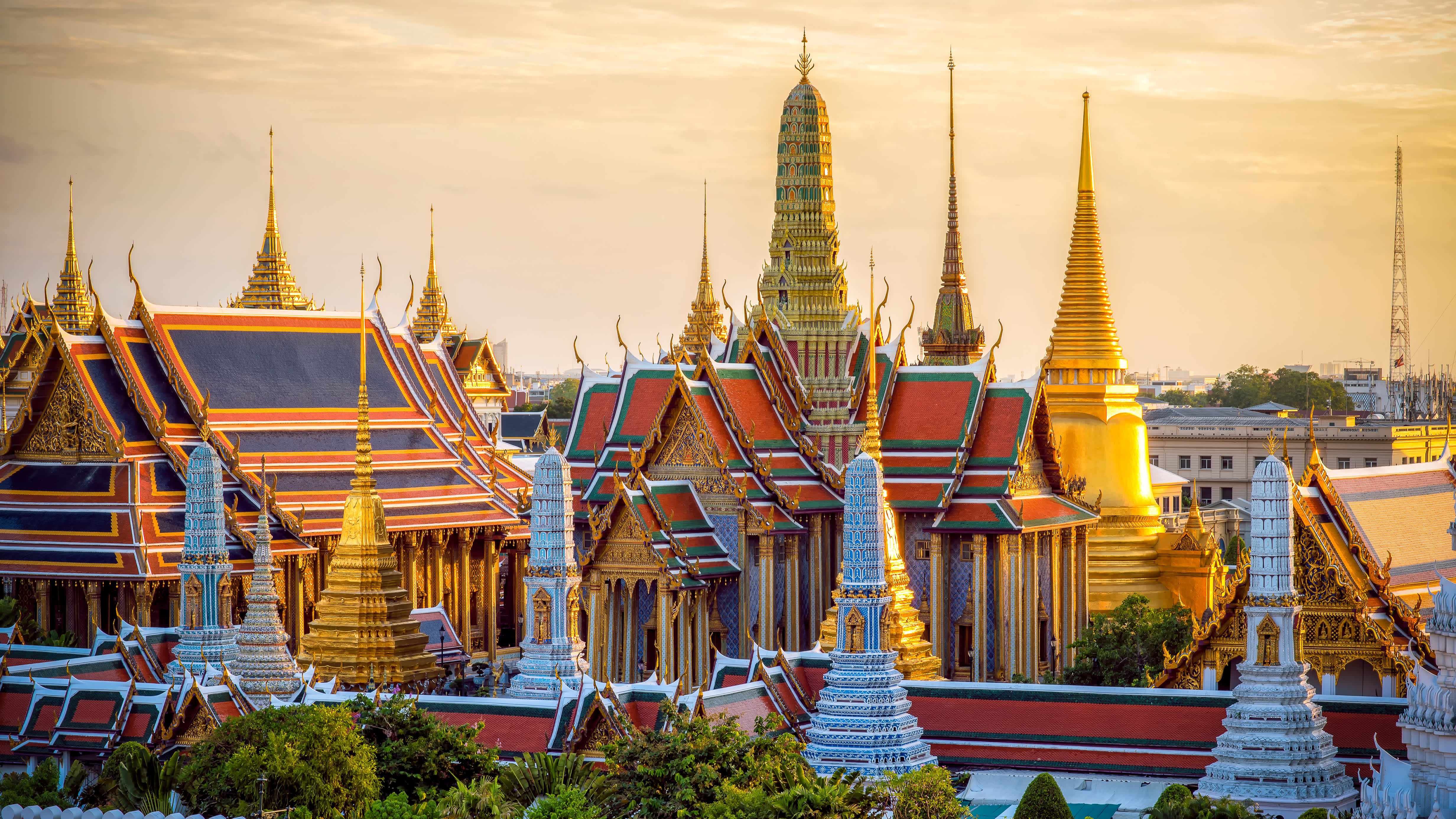 Stunning panorama of Bangkok's Grand Palace at sunset with golden spires and ornate temple rooftops